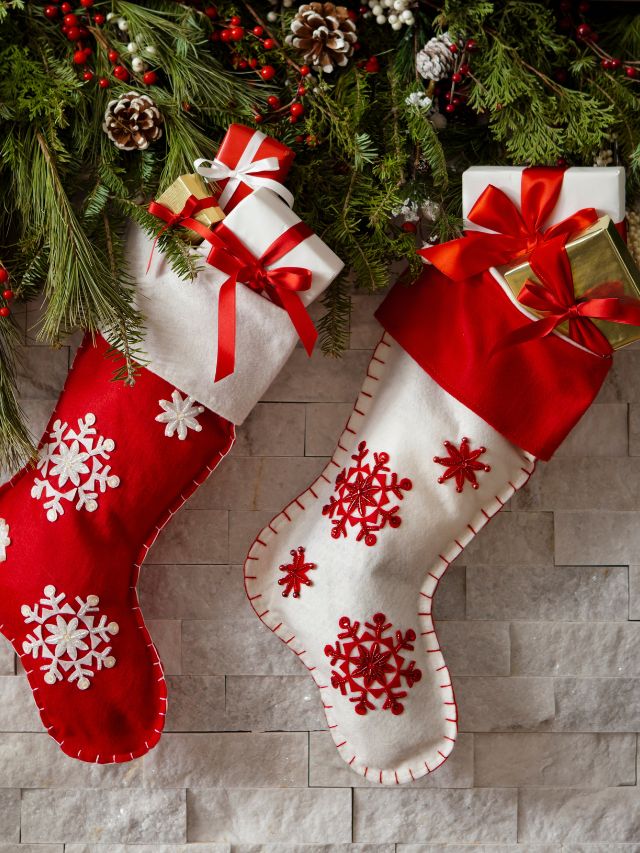 Two christmas stockings hanging on a brick wall.