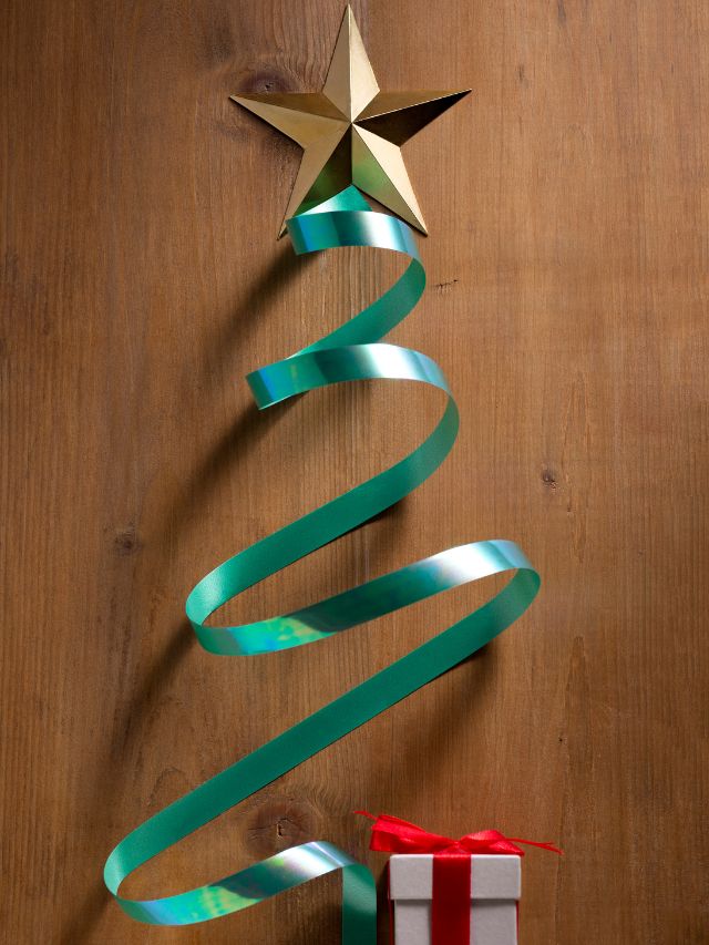 A christmas tree made of ribbon and a gift box on a wooden background.