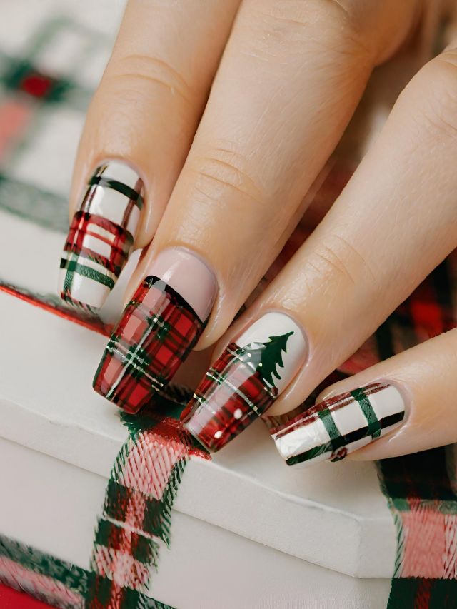 A woman's nails are decorated with plaid and christmas trees.