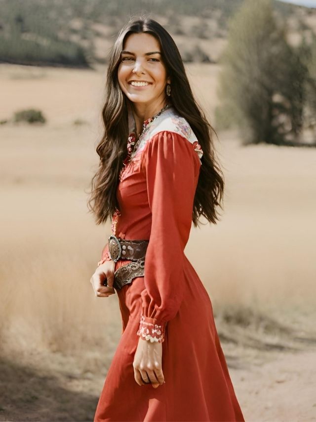 A woman in a red dress smiling in a field.