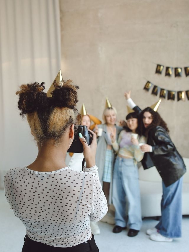 A woman taking a photo of her friends at a party.
