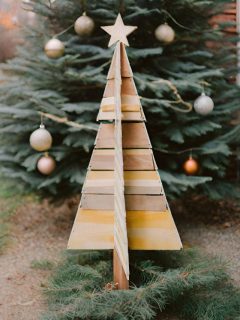 A wooden christmas tree in front of a tree.