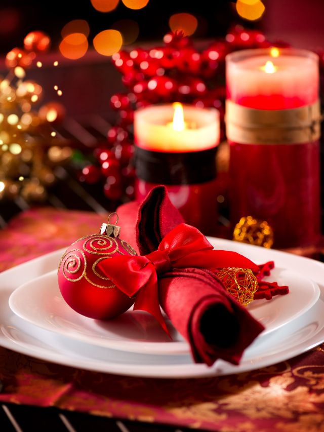 Christmas table setting with red ornaments and candles.