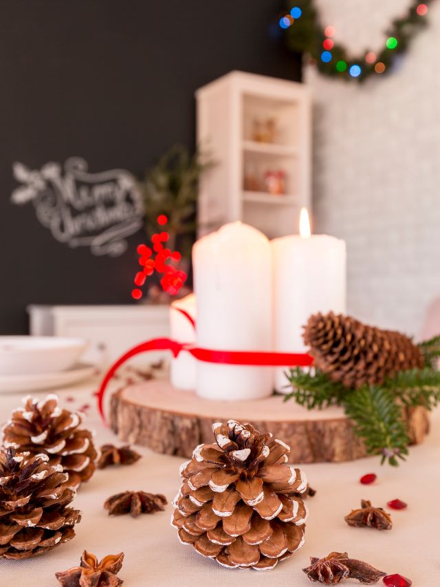 A christmas table setting with pine cones and candles.