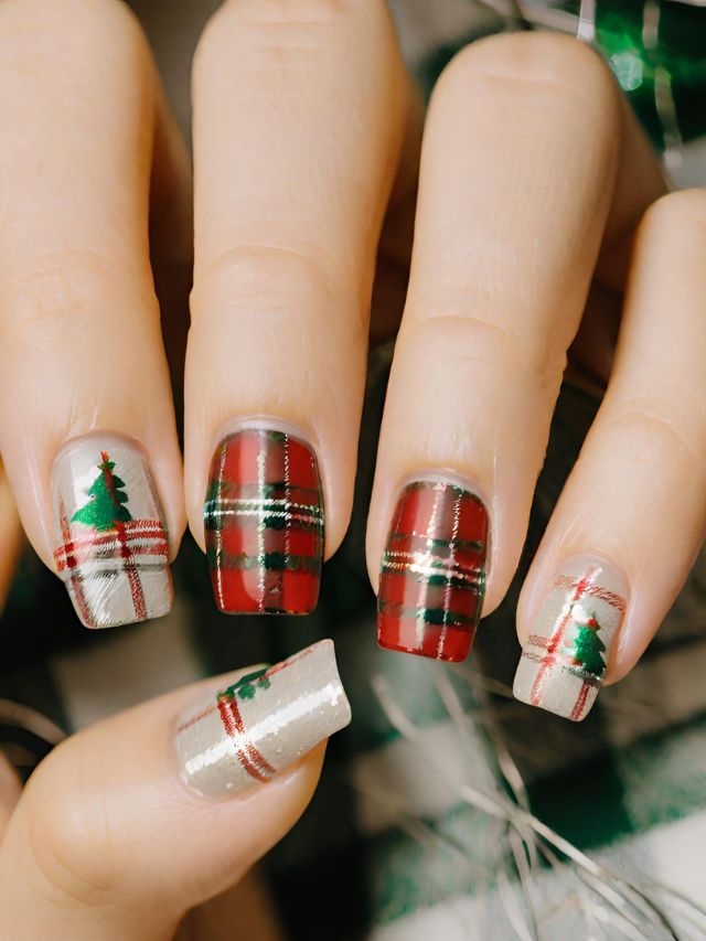 A woman's nails are decorated with christmas trees and plaids.
