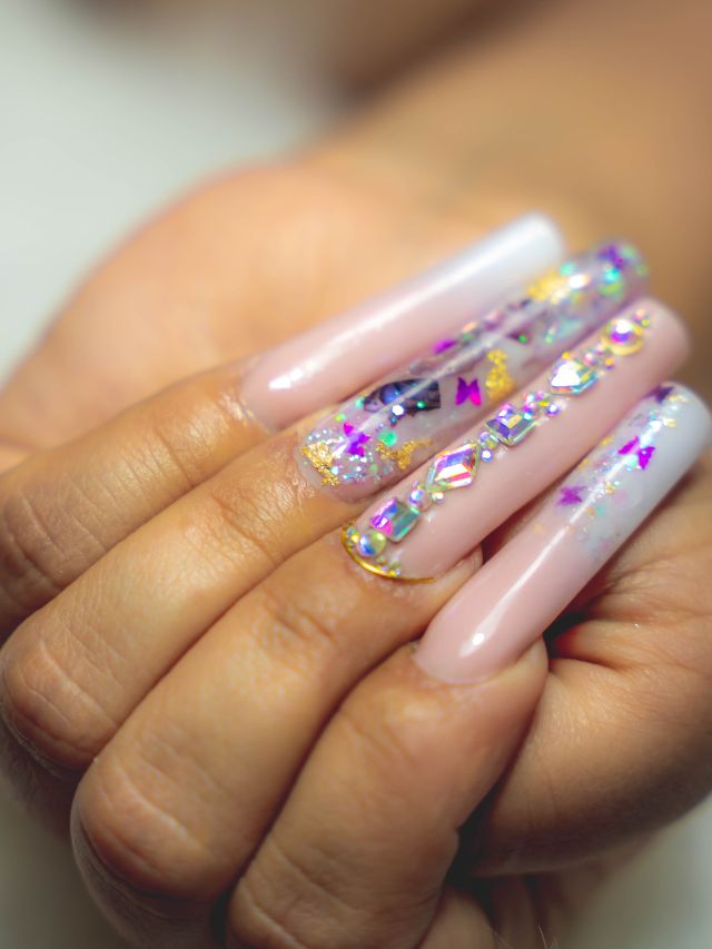 A woman's hand holding a pink and white manicure.