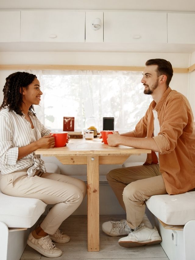 A man and woman sitting at a table in an rv.