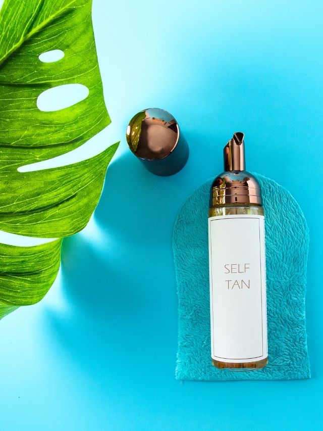 A bottle of self tan and a leaf on a blue background.