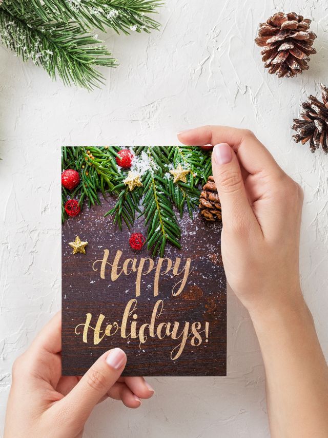 A person holding up a happy holidays card thank you card for christmas
