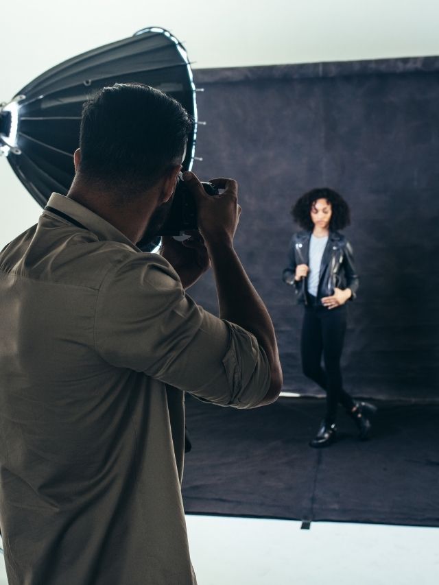 A man is taking a picture of a woman in a studio.