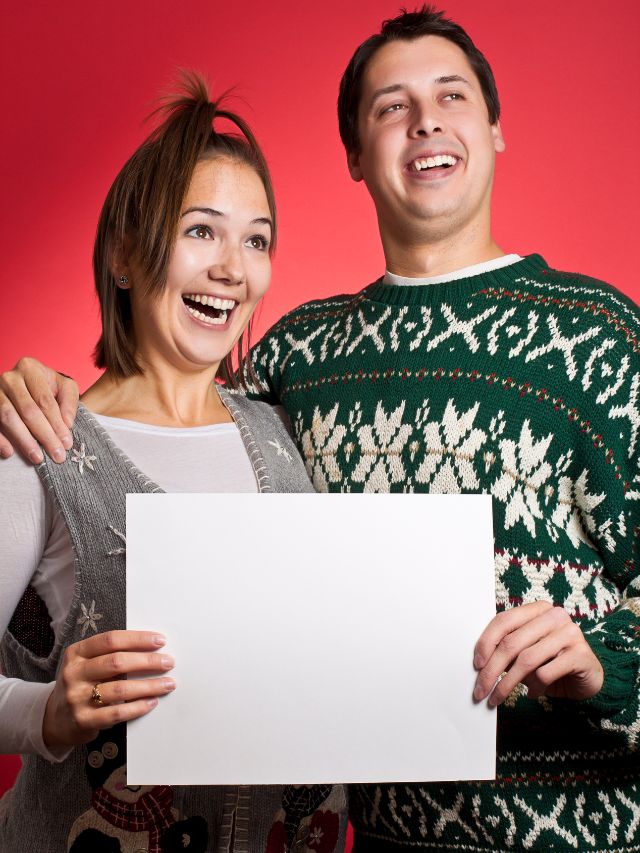 A young couple holding a blank sign over a red background.