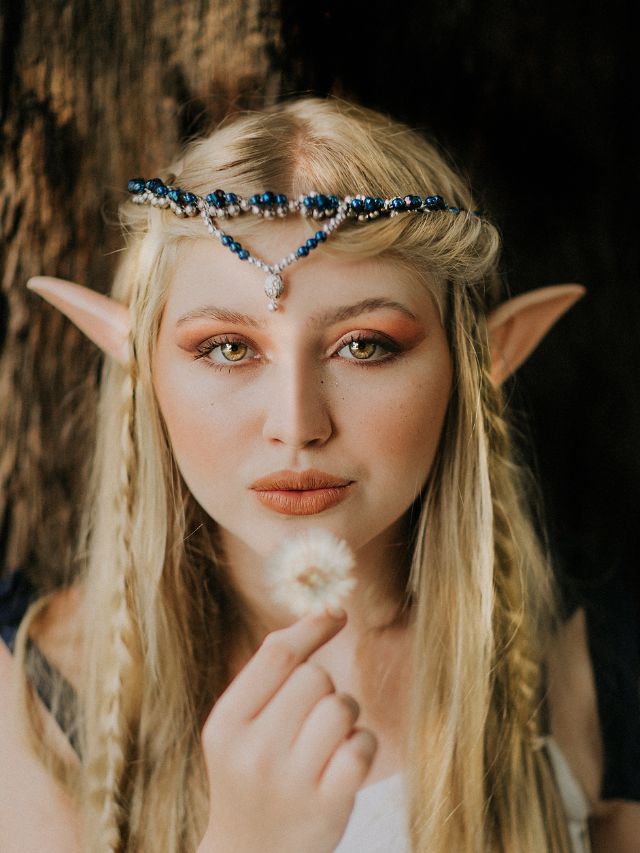 A young woman in an elf costume holding a dandelion.