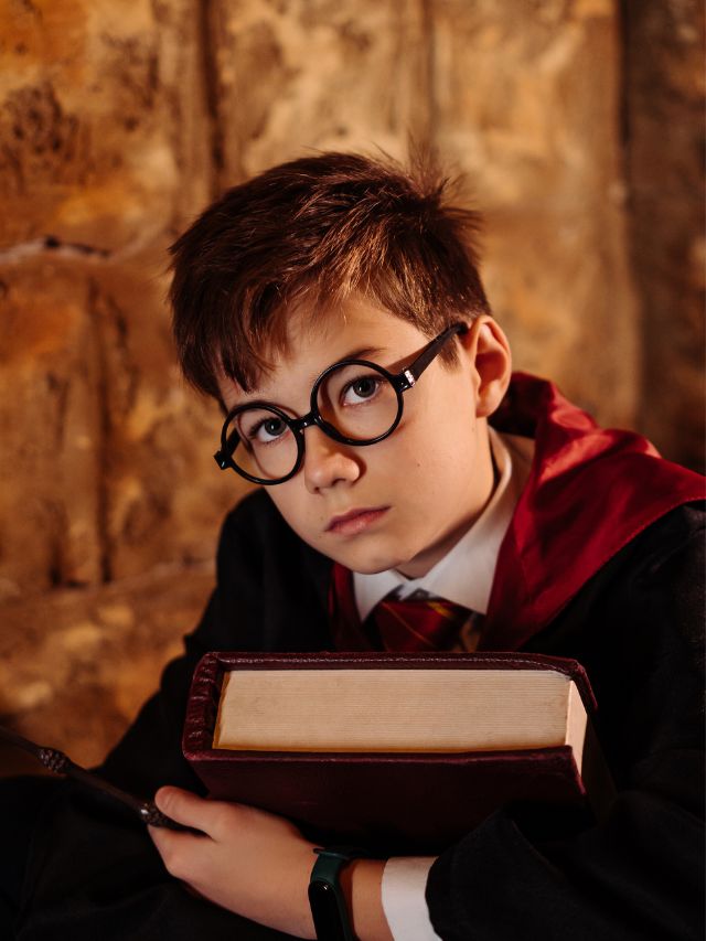 A boy in a harry potter costume holding a book.