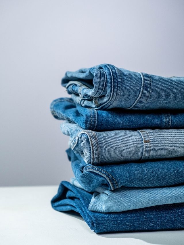 A stack of blue jeans on a white background.