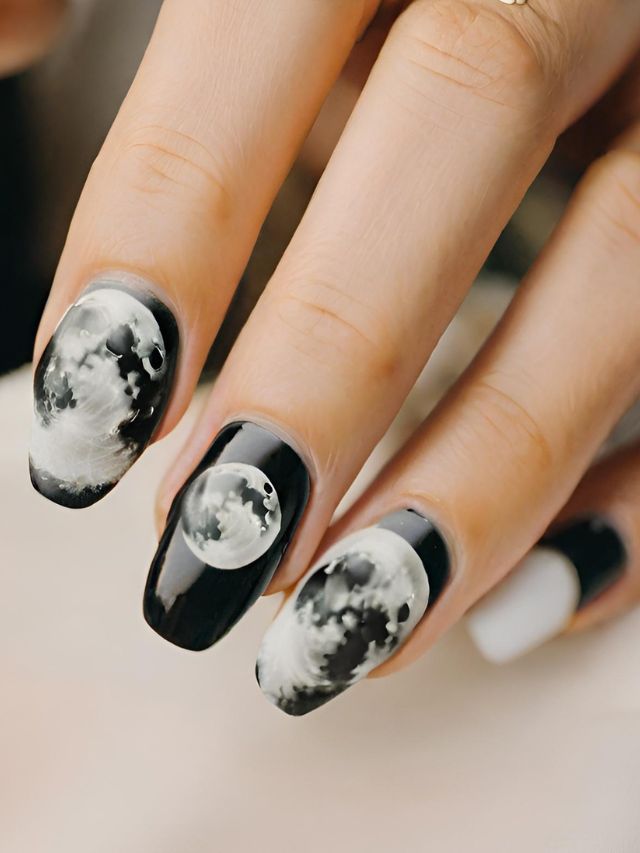 A woman is holding a black and white nail with a moon on it.