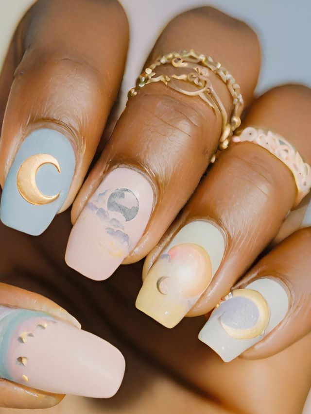 A woman's nails are decorated with moons and stars.