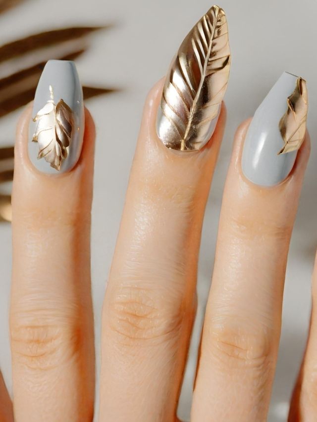A woman's nails with gold leaves on them.