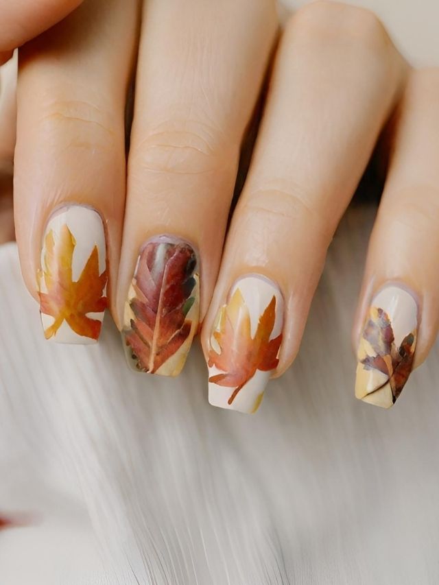 A woman's nails are decorated with autumn leaves.