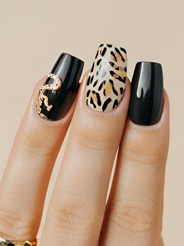 A woman's hand with trendy black and gold leopard print nails, showcasing the painting one nail a different color trend.