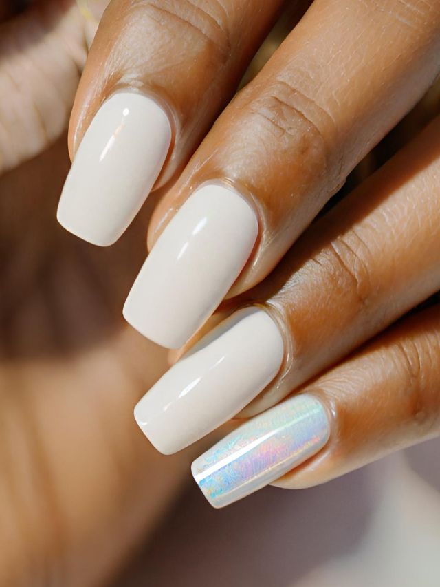 A woman's hand experimenting with the latest nail trend - painting one nail a different color, showcasing a mesmerizing white opal polish.