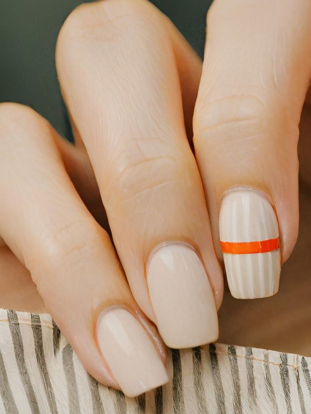 A woman's hand sporting a trendy beige nail with an eye-catching orange stripe.