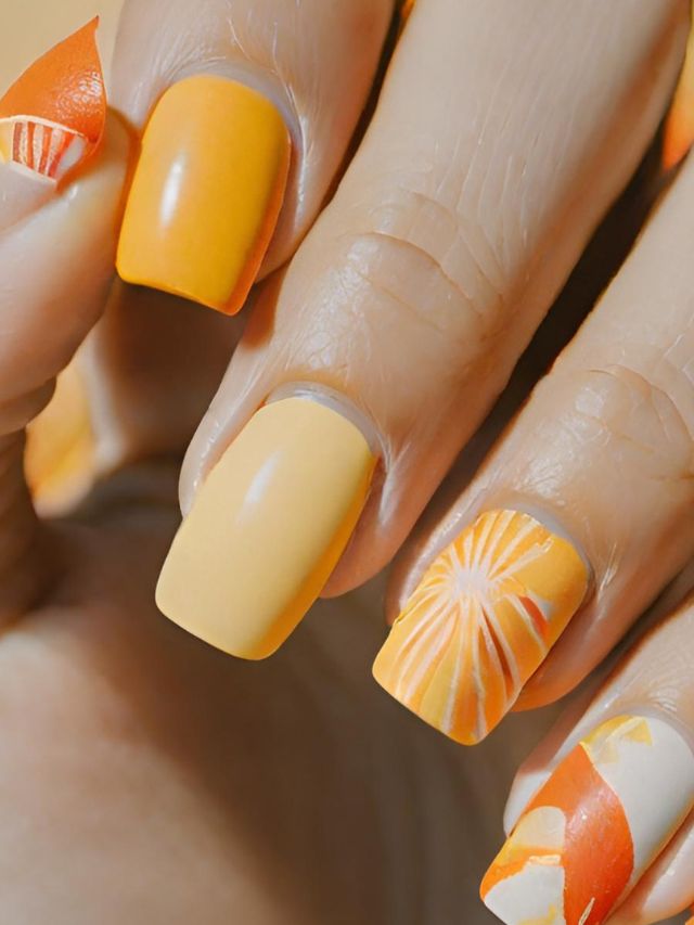 A woman's nails with orange and white designs.