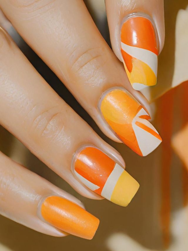 A woman's nails with orange and white designs.