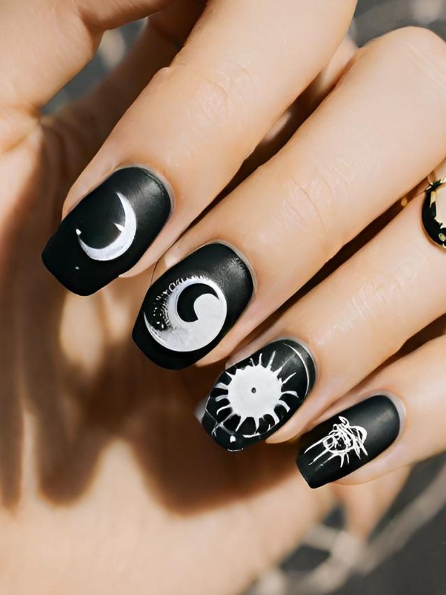 A woman is holding a black nail with a moon and star on it, showcasing a unique zodiac nail design.