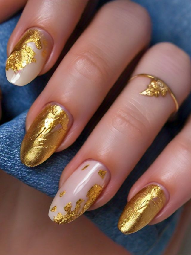 A woman's nails are elegantly decorated with gold foil, showcasing a luxurious and eye-catching nail design.