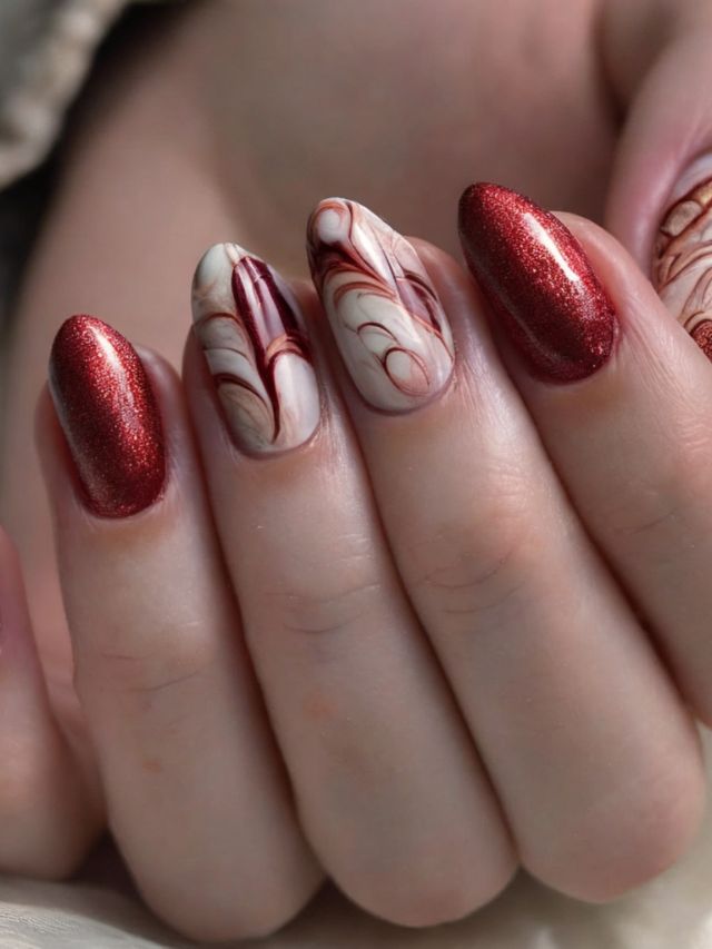 A woman's gorgeous almond-shaped nails with red and white marble designs.