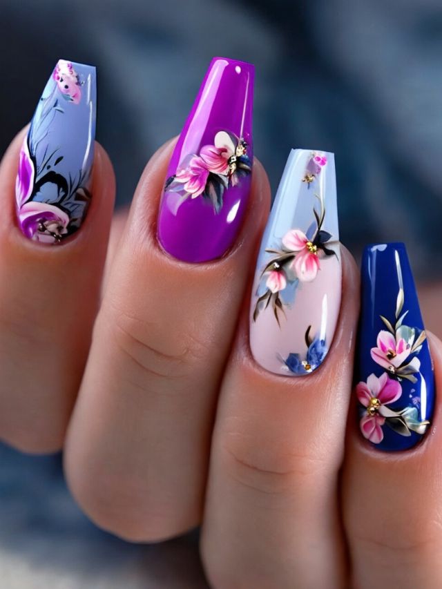A woman's nails with blue and purple flowers on them, featuring a nail design in pink, purple, and blue.