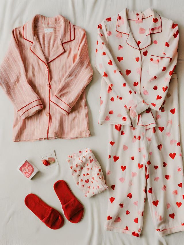 Valentine's day pajamas and slippers laid out on a bed.