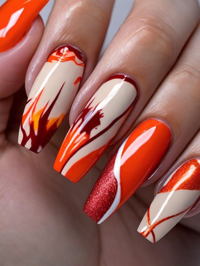A woman's nails with orange and white fall nail designs.