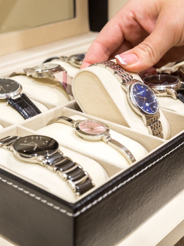 A woman is putting watches into a box.