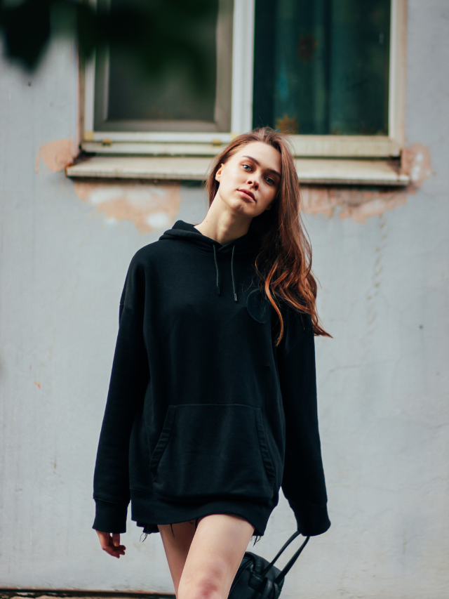 A woman wearing a black hoodie and shorts.