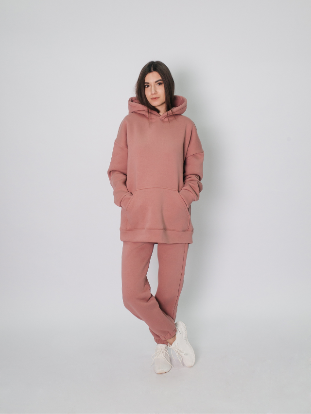 The model is wearing a pink hoodie and sweatpants.