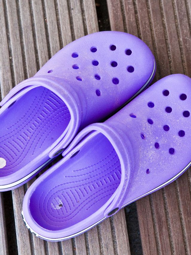 A pair of purple crocs on a wooden deck.