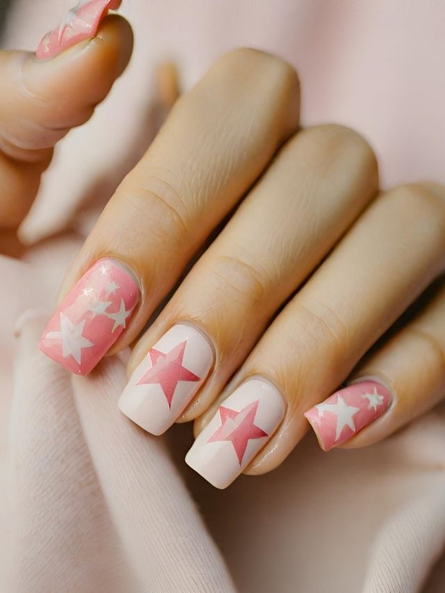 A woman's pink and white nails adorned with stars, perfect for Valentine's Day.