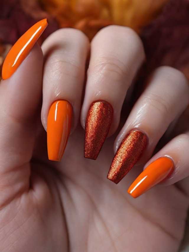 A woman's hand with orange nails and leaves.