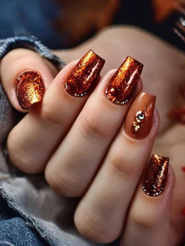 A woman's nails with gold glitter and leaves on them.