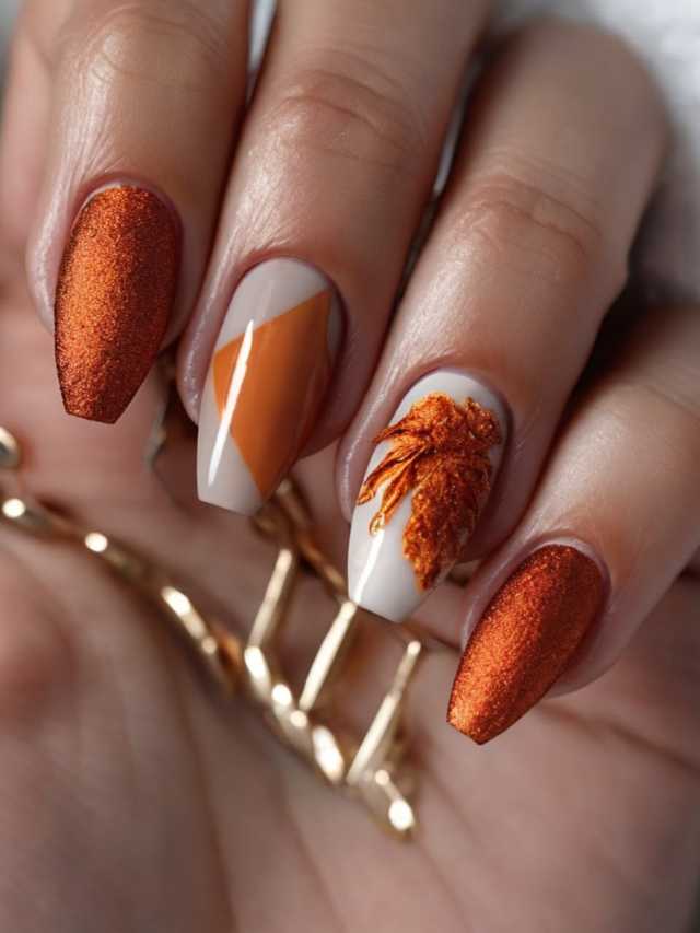 A woman's hand holding an orange and white nail design.
