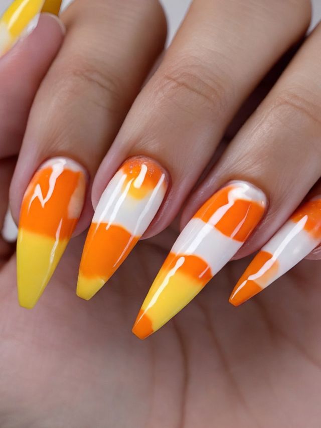 A woman's hand with orange and white candy corn nails.