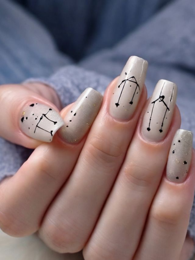 A woman's nails with zodiac signs on them.