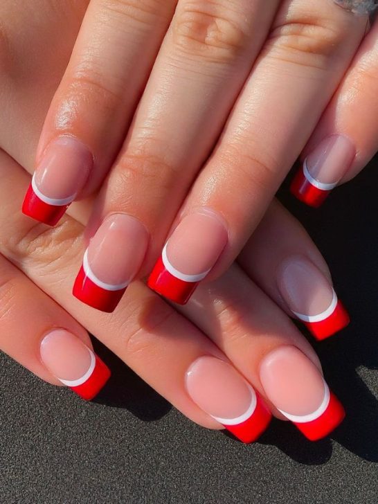 A woman's hands with red and white nail designs.
