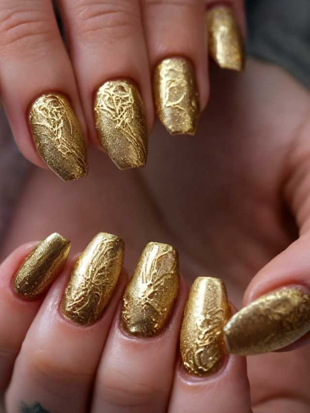 A woman's hands with gold nail polish on them.
