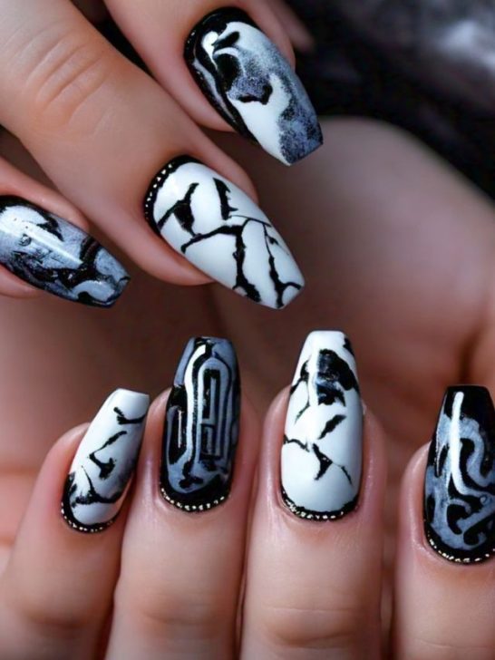 A woman's nails are decorated with black and white designs.