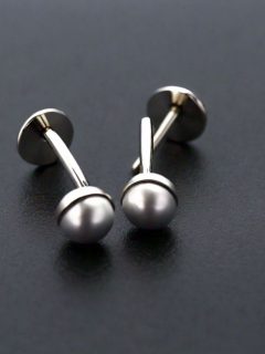 A pair of silver stud earrings with pearls.
