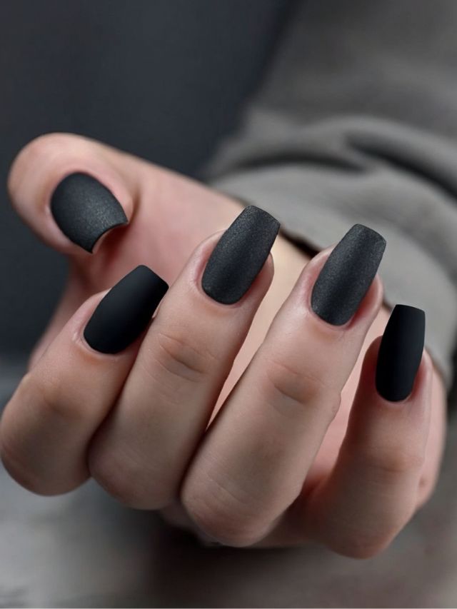 A woman's hand with black matte nails featuring trendy nail designs.