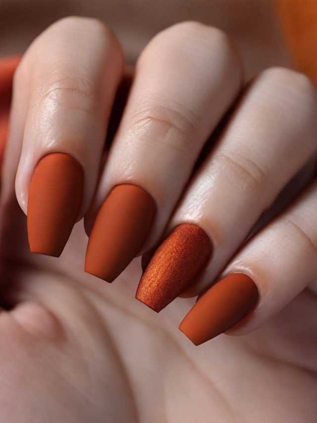 A woman's hand holding a pair of orange nails.