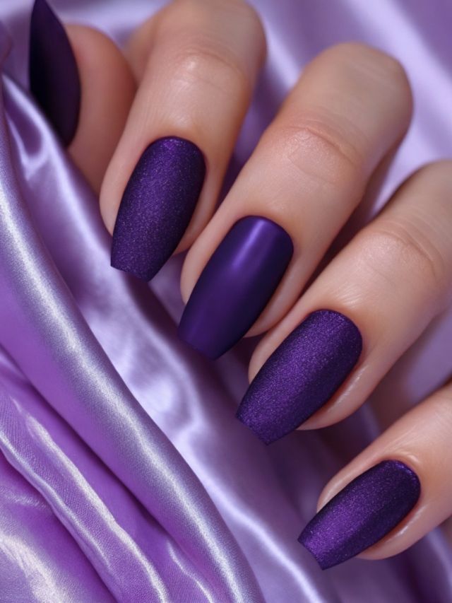 A woman's hand with purple nails on a satin fabric.
